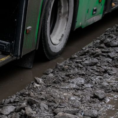 people are standing at a bus stop, getting on a bus stepping over uncleared snow and mud, special services do not clean the city