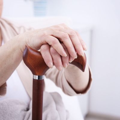 Female hands holding walking stick closeup