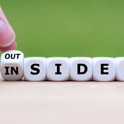 Hand turns a dice and changes the word "OUTSIDER" to "INSIDER" (